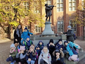 Dzieci z klas 1 prezentują się do zdjęcia pod pomnikiem skrzypka w Toruniu.