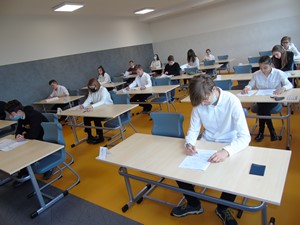 Uczniowie siedzą przy ławeczkach w klasie i piszą próbny egzamin ósmoklasisty.