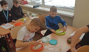 Dwoje uczniów siedzących przy szkolnej ławce przygotowuje gofry do zjedzenia.