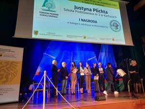 Pani Justyna Plichta na scenie odbiera I nagrodę w "Wojewódzkim konkursie na scenariusz zajęć o tematyce morskiej – Zajęcia na fali".