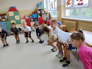 Dzieci z oddziału przedszkolnego (zerówka 01) ćwiczą w sali lekcyjnej.