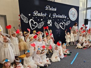 Dzieci z oddziałów przedszkolnych prezentują na sali gimnastycznej część artystyczną podczas uroczystości z okazji Dnia Babci i Dziadka.