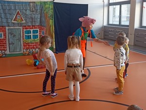 Dzieci z oddziału przedszkolnego stoją na sali gimnastycznej podczas spektaklu ekologicznego "Przygody Świnek".
