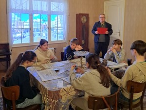 Uczniowie klasy 7a siedzą przy stole podczas zwiedzania Muzeum II Wojny Światowej.