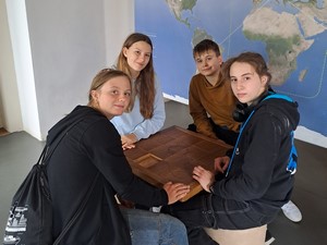 Uczniowie uczestniczący w mobilności do szkoły w Czechach (ERASMUS+) siedzą przy stoliku podczas zwiedzania "Domu Wody".