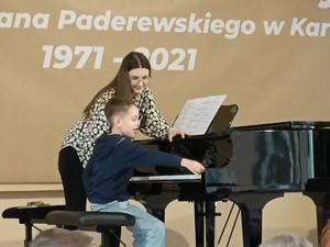 Nauczycielka Szkoły Muzycznej instruuje ucznia podczas gry na fortepianie.