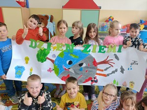 Dzieci z oddziału przedszkolnego (zerówka 01) stoją i prezentują się do zdjęcia trzymając plakat pt. "Dzień Ziemi".