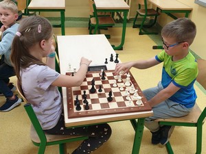 Dzieci uczestniczące w szkolnym turnieju szachowym stoją i prezentują się do zdjęcia.