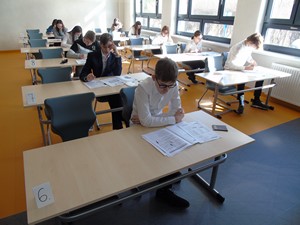 Uczniowie siedzą przy ławeczkach w klasie i piszą próbny egzamin ósmoklasisty.