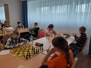 Jakub Sieniek siedzi przy stole, podczas gry w szachy na turnieju.