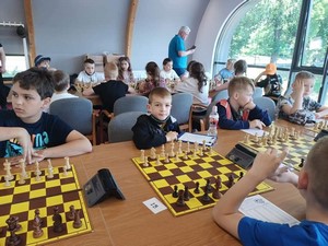Uczeń Jakub Sieniek siedzi przy szachownicy, przy stole podczas turnieju w Bydgoszczy.