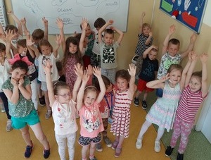 Dzieci z oddziału przedszkolnego (zerówka 02) stoją z podniesionymi rękoma - prezentują się do zdjęcia.
