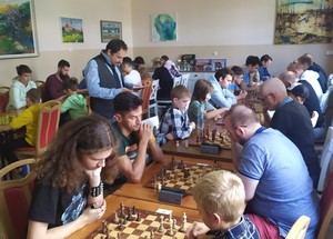 Szachiści siedzący przy stołach z planszami szachowymi.