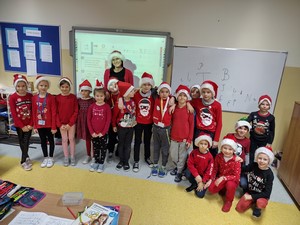 Uczniowie klasy 1a prezentują się wraz z wychowawczynią w czapkach św. Mikołaja.