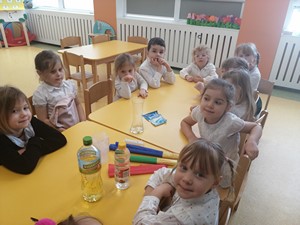Dzieci z oddziału przedszkolnego (4 - latki) siedzą przy stoliku i oczekują na rozpoczęcie zabaw z kolorami.