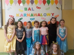 Dzieci z oddziału przedszkolnego (zerówka 02) prezentują się do zdjęcia przy tablicy z napisem "Bal Karnawałowy".