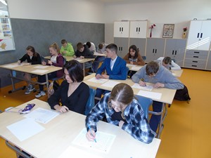 Uczniowie siedzą w ławeczkach i rozwiązują zadania podczas Matematycznego Konkursu Kangur.