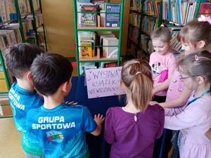 Uczniowie stoją przed stolikiem z napisem "Wystawa książek niewidzialnych".