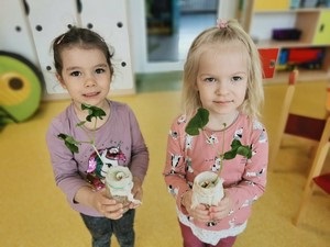 Dwójka dzieci z oddziału przedszkolnego 3 latków prezentuje sadzonki fasoli.
