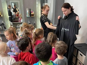 Dzieci z oddziału przedszkolnego (4 - latki) słuchają prezentacji pani fryzjerki w gabinecie fryzjerskim.