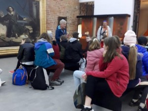 Uczniowie siedzą na siedziskach w Muzeum Mikołaja Kopernika we Fromborku.