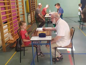 Dziecko z oddziału przedszkolnego (zerówka 03) - Maja Wesołowska gra przy stoliku w dorosłą osobą w szachy.