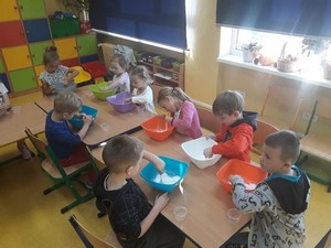 Dzieci z oddziału przedszkolnego (zerówka 01) siedzą przy stolikach i wykonują prace manualne.