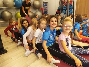 Uczniowie klasy 1b siedzą na podłodze w klubie fitness Forma.