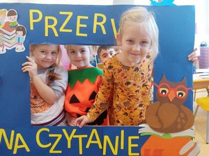 Dzieci z oddziału przedszkolnego prezentują się z napisem "Przerwa na Czytanie".