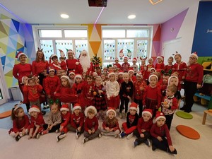 Dzieci z oddziałów przedszkolnych prezentują się do zdjęcia z Mikołajem.