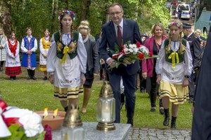 Delegacja (dyrektor szkoły, dwie uczennice) składają kwiaty pod pomnikiem poległych mieszkańców Kartuz.