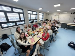 Uczniowie klasy 8b siedzą wokół stołu podczas spotkania opłatkowego.