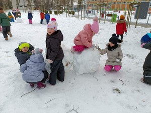 Dzieci z oddziału przedszkolnego (4 i 5 - latki) lepią bałwana na śniegu.