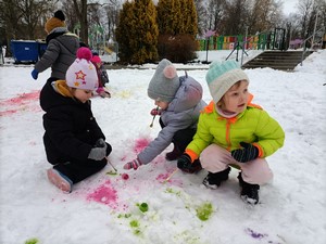 Dzieci z oddziału przedszkolnego (4 - latki) na trawniku przed szkołą malują farbkami po śniegu.