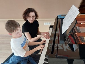 Nauczycielka ze Szkoły Muzycznej w Kartuzach wraz z chłopcem z zerówki gra na fortepianie.