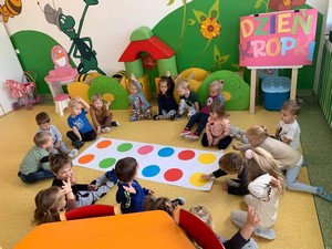 Dzieci z oddziałów przedszkolnych (5 latki) siedzą na podłodze wokół planszy z kropkami.