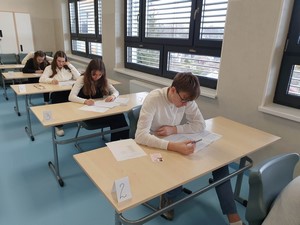 Uczniowie z klas ósmych siedzą przy stolikach i rozwiązują próbny egzamin ósmoklasisty.
