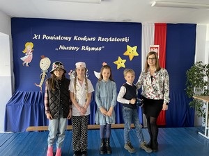 Uczniowie uczestniczący w XI Powiatowym Konkursie Recytatorskim "Nursery Rhymes" wraz z opiekunką p. D. Klasą prezentują się do zdjęcia.