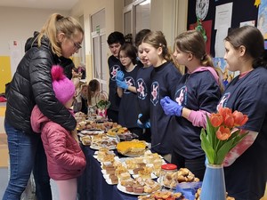 Uczniowie ze Szkolnego Koła Wolontariatu "Serce" sprzedają ciasta.
