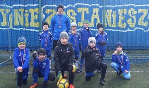 Uczniowie ze Szkoły Podstawowej Nr 2 im. Mikołaja Kopernika w Kartuzach uczestniczący w turnieju piłkarskim prezentują się do zdjęcia wraz z treneram.