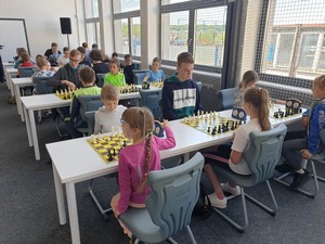 Szachiści siedzą przy stolikach i grają w szachy podczas XXIV Otwarty Szachowy Turniej o "Puchar Stolema".