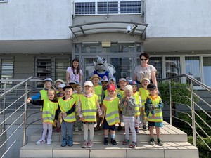 Dzieci z oddziału przedszkolnego (3 - latki) wraz z wychowaczynią prezentują się do zdjęcia przed wejściem na Komendę Policji w Kartuzach.
