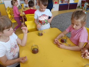 Dzieci z oddziału przedszkolnego (3 - latki) siedzą przy stoliku i wykonują świecę zapachową podczas warsztatów.