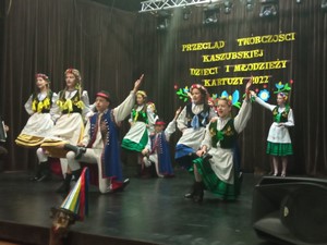 Uczestnicy zespołu "Słunoszka" tańczą na scenie podczas Przeglądu Twórczości Kaszubskiej Dzieci i Młodzieży.