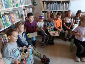 Dzieci z oddziału przedszkolnego (5 - latki) siedzą w sali Miejskiej i Powiatowej Biblioteki w Kartuzach i słuchają pani bibliotekarki.