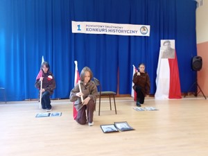 Uczennice z klasy 7 prezentują układ patriotyczny podczas I Powiatowego Drużynowego Konkursu Historycznego w Szkole Podstawowej w Grzybnie.
