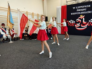 Dziewczęta wykonują taniec z flagami podczas apelu z okazji Święta Odzyskania Niepodległości.