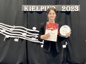 Uczennica Alicja Marszk (7b) wraz z nagrodą prezentuje się do zdjęcia podczas VI Gminnego Konkursu Pieśni Patriotycznej w Kiełpinie.