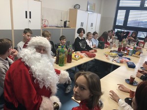 Uczniowie z klasy 7b siedzą przy wigilijnym stole wraz ze Św. Mikołajem.