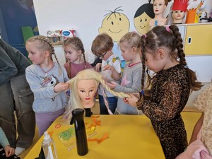 Dziewczęta z oddziału przedszkolnego (oddział 5 – latków) czeszą włosy na sztucznej głowie.